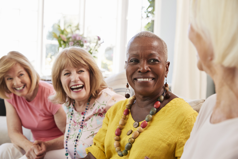 A group of women in a senior living community laugh together.