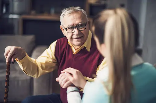 Woman Embracing and Supporting Senior Man with Cane