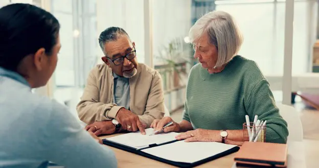 a senior couple looking over documents with their financial advisor