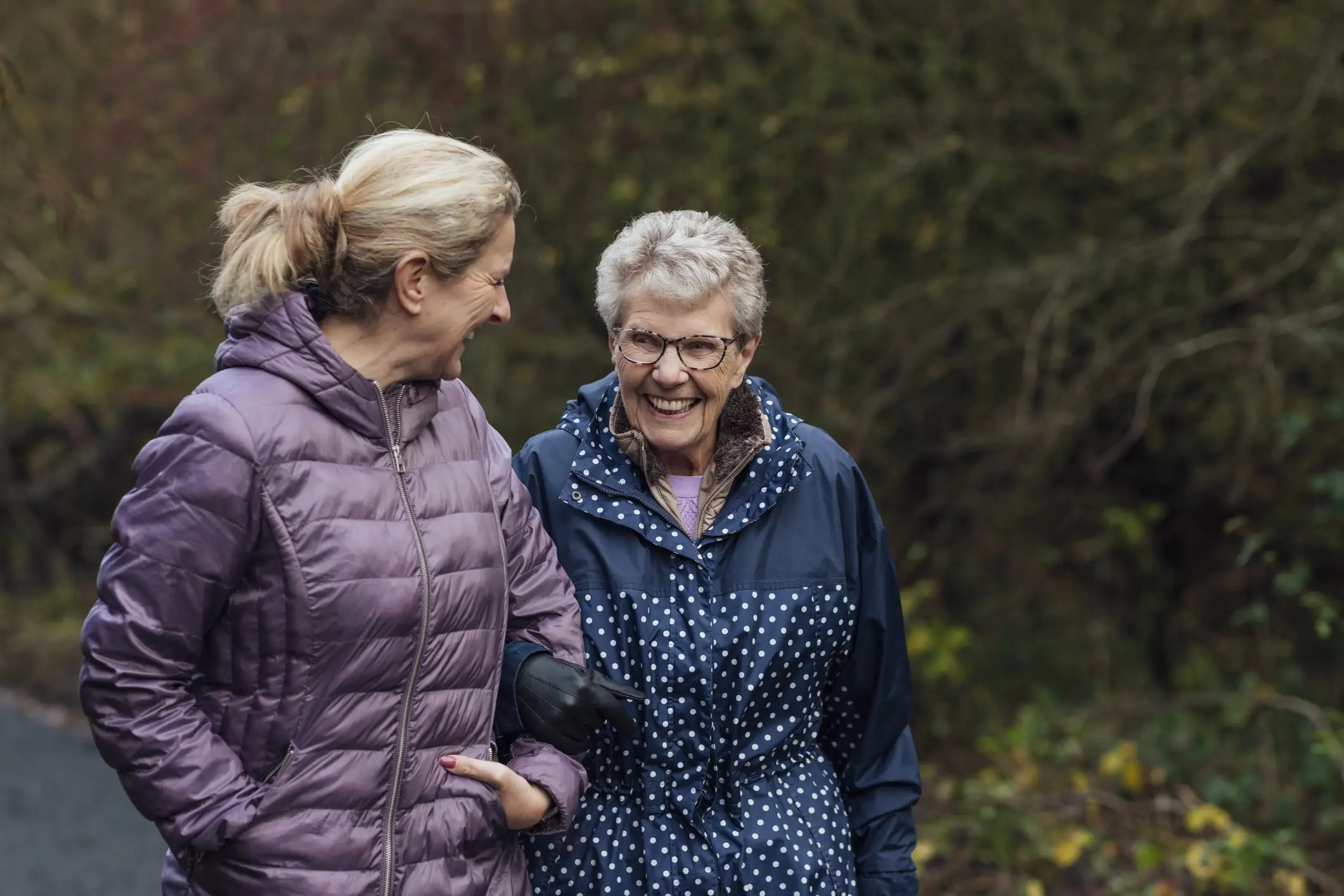 Two senior woman walking together arm in arm.