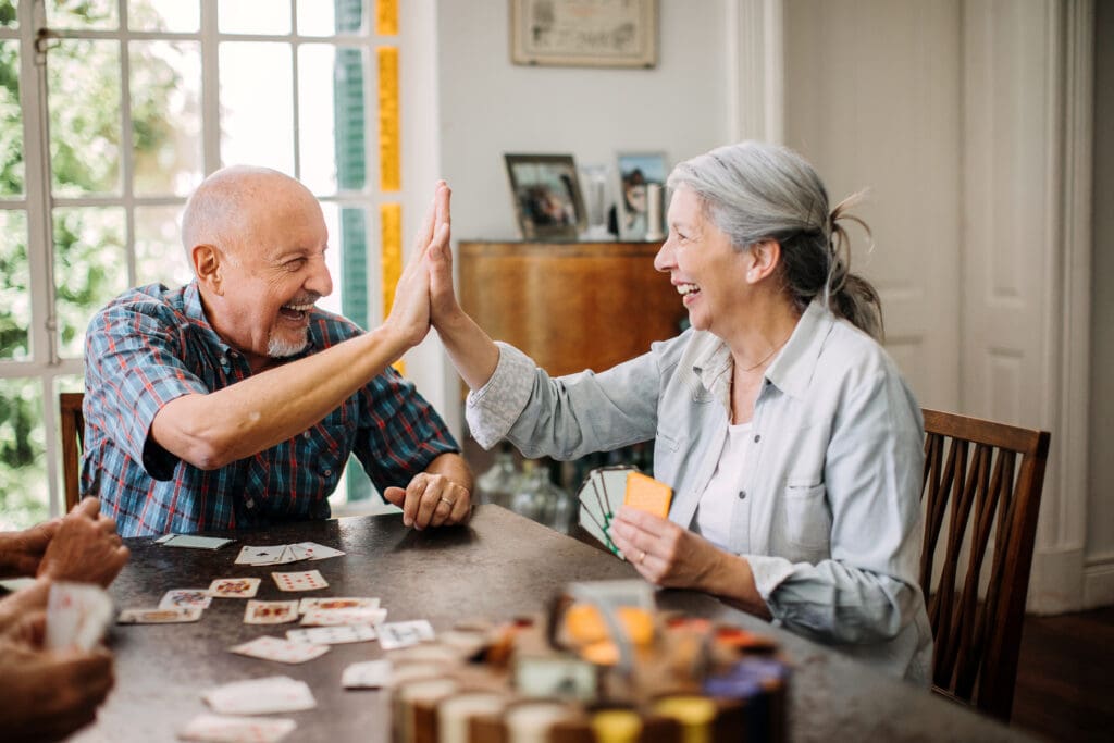 Older couple high-fiving playing cards