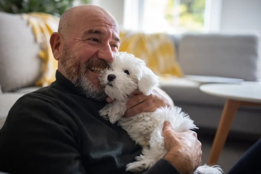 Senior man holding a small dog while exploring the benefits of pet ownership at Wyndemere in Wheaton, IL.