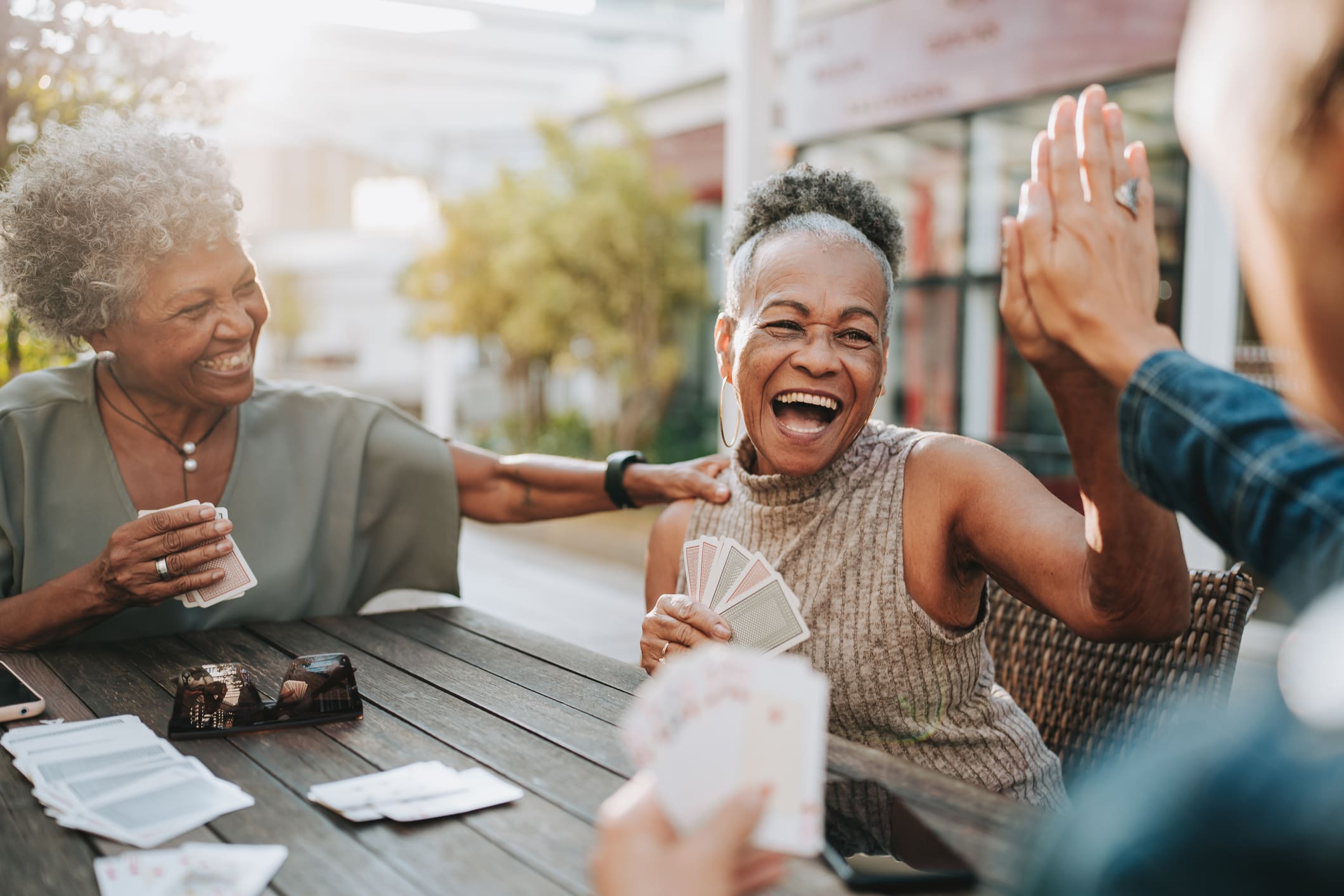 Senior woman high fives friend at the card table