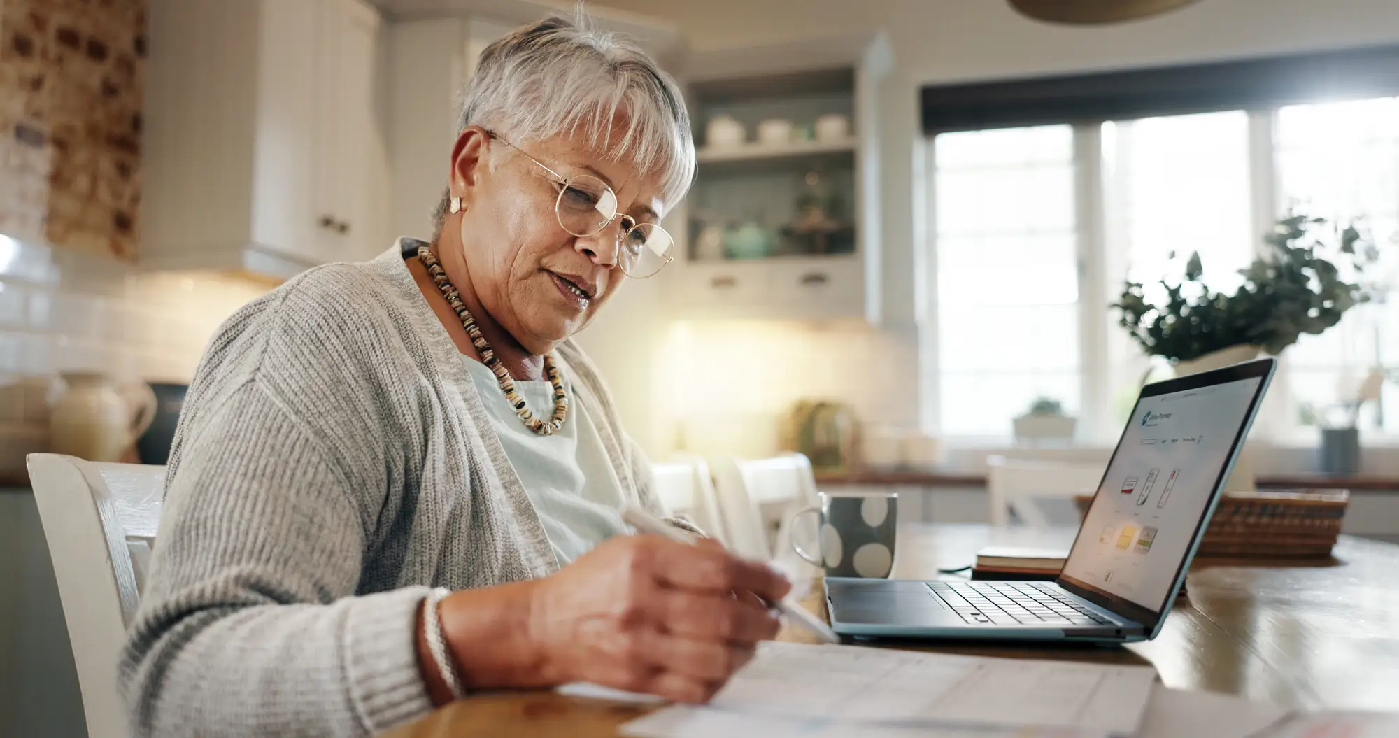 An elderly woman looking through her laptop to find tax breaks for seniors in Wheaton, IL at Wyndemere.