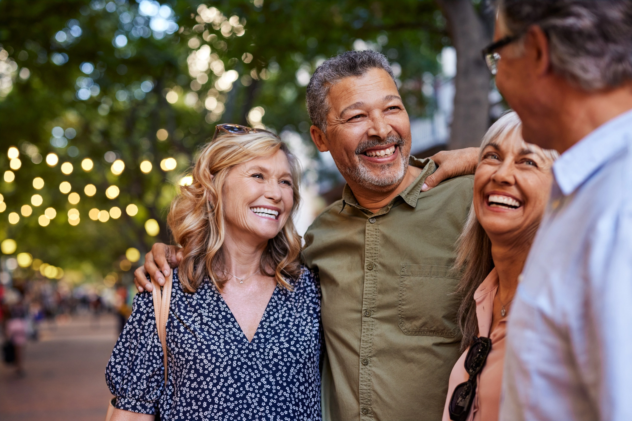 Two elderly couples hugging and smiling while exploring things to do in Wheaton for seniors.