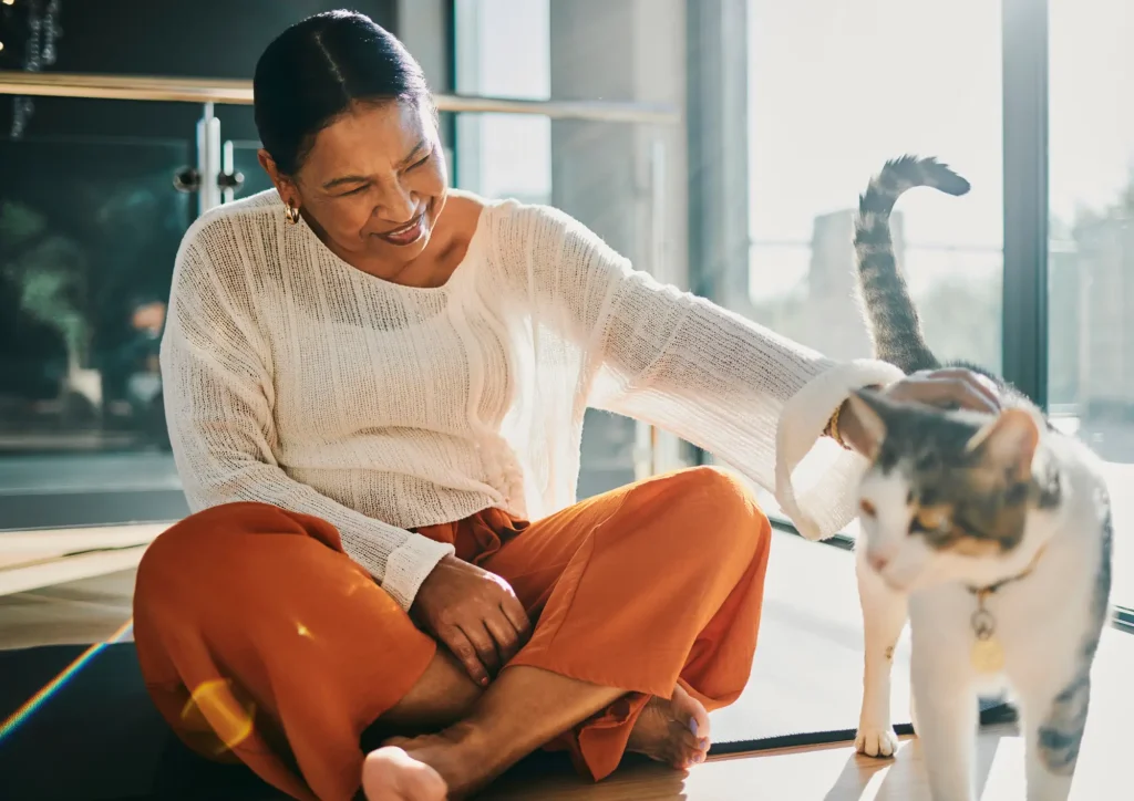 A senior woman rubbing a cat while exploring the benefits of pet ownership at Wyndemere in Wheaton, IL.